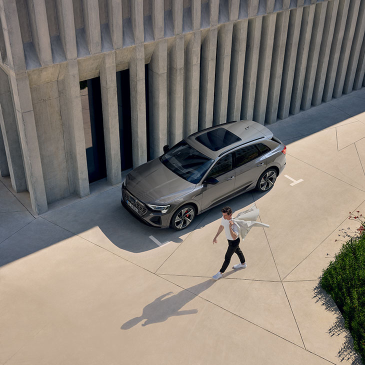 Mann geht an einem parkenden Audi Q8 e-tron vorbei