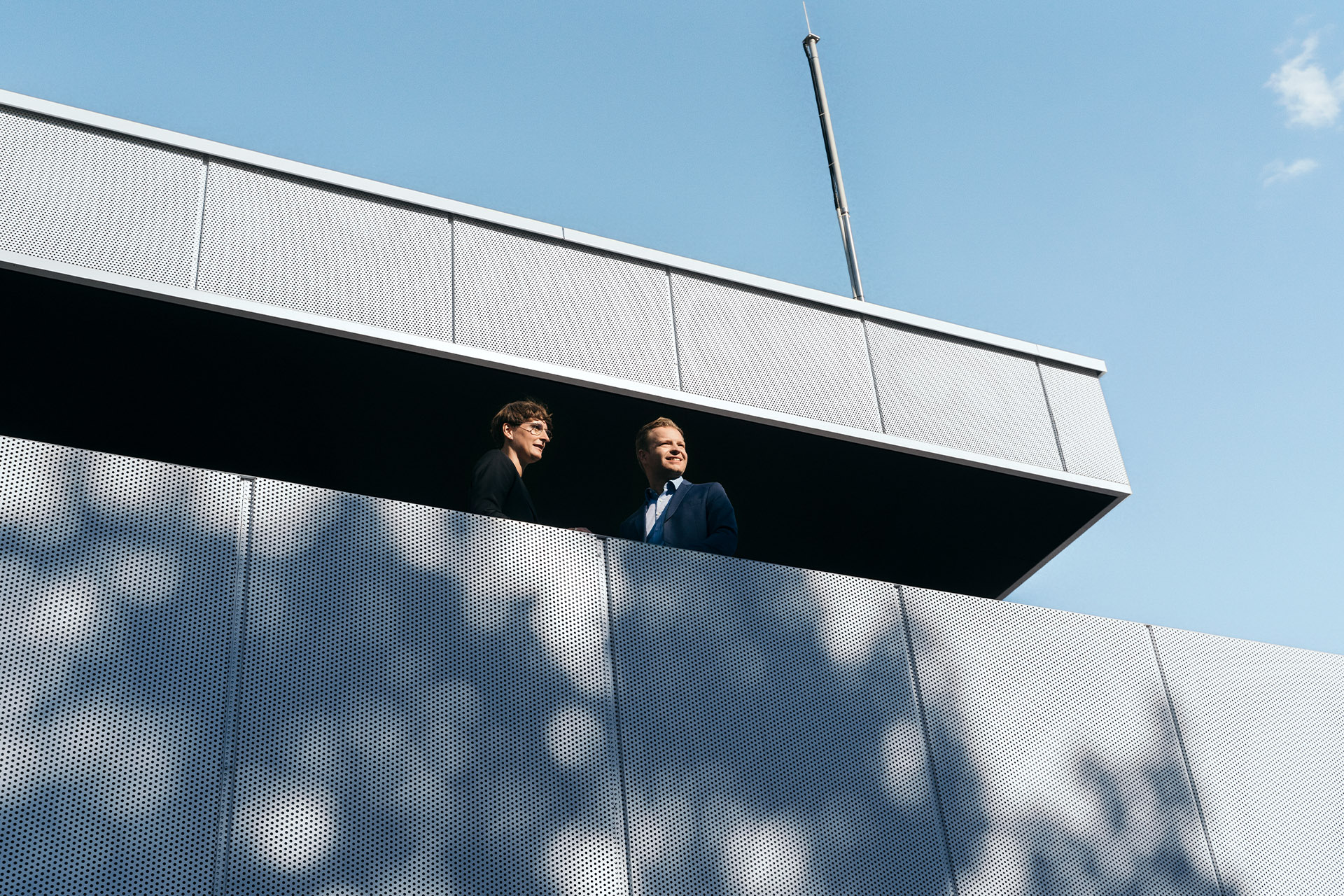 Gli esperti di sostenibilità Johanna Klewitz e Malte Vömel guardano dal balcone della lounge dell'hub di ricarica Audi.