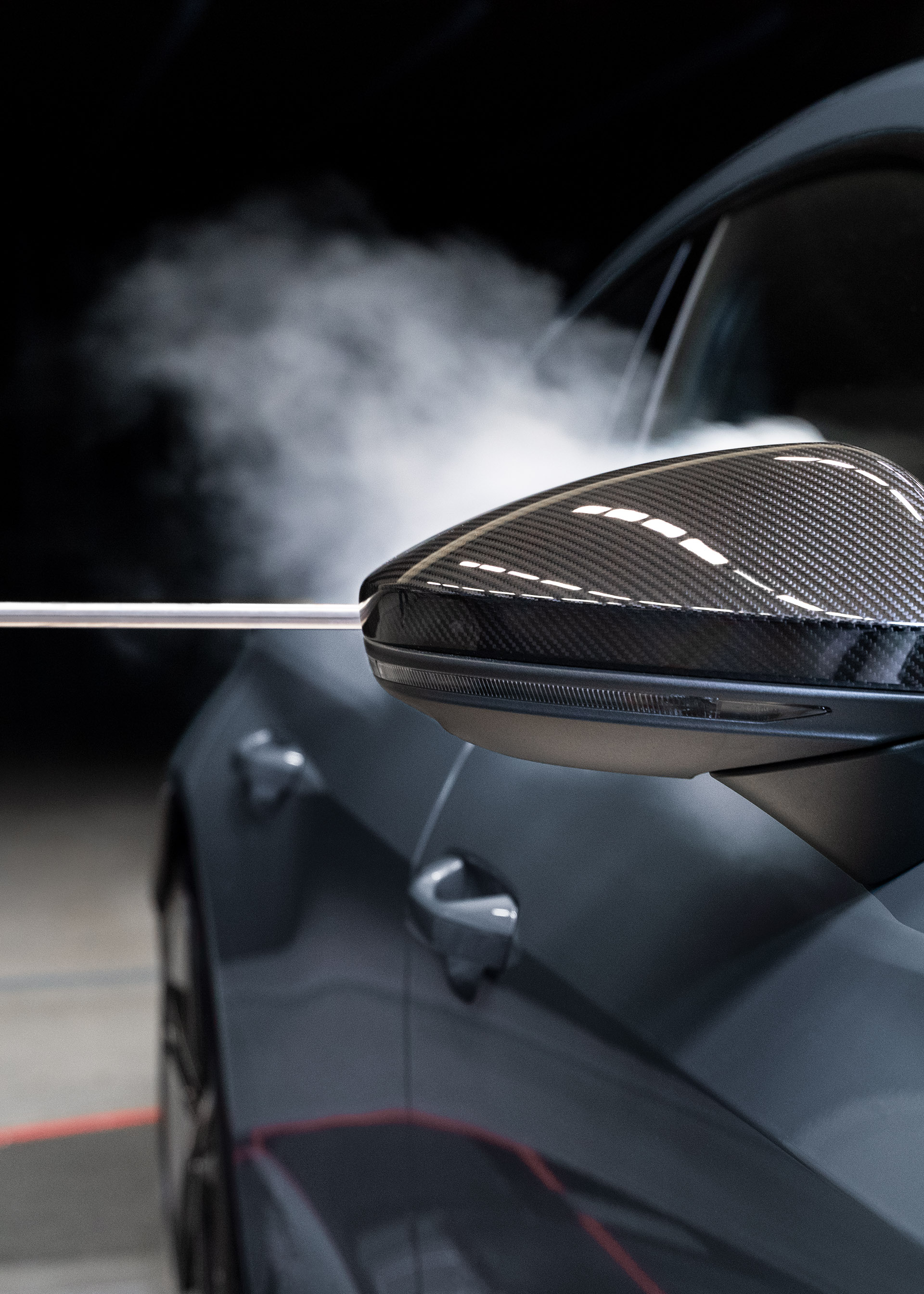 De la fumée s'écoule derrière le rétroviseur extérieur, le long de la carrosserie de l'Audi RS e-tron GT.  