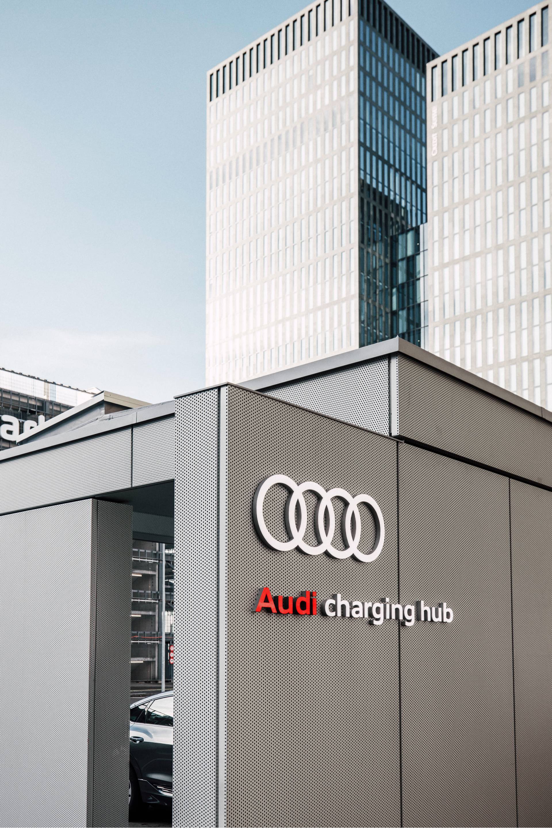 Audi charging hub, en arrière-plan, des immeubles.